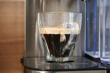 Freshly brewed coffee in a glass sitting on a coffee machine