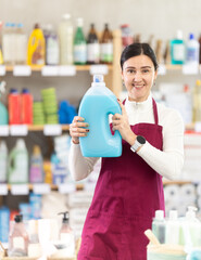 Middle-aged saleswoman offering detergent and cleaning gel in the household department of a...