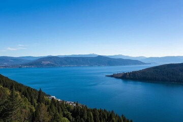 a view of a lake surrounded by trees and mountains with a blue sky