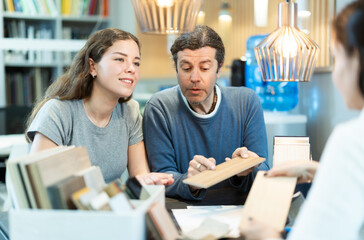 Sitting at the table, married couple consults with furniture store manager about choosing a...