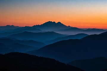 Obraz premium mountains are silhouetted against a sunset sky with a hazy sky