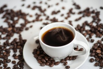 Fototapeta premium A cup of steaming coffee surrounded by coffee beans 