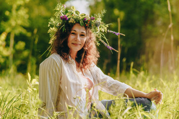 Woman with natural flower crown relaxing in rural summer field, offline moment