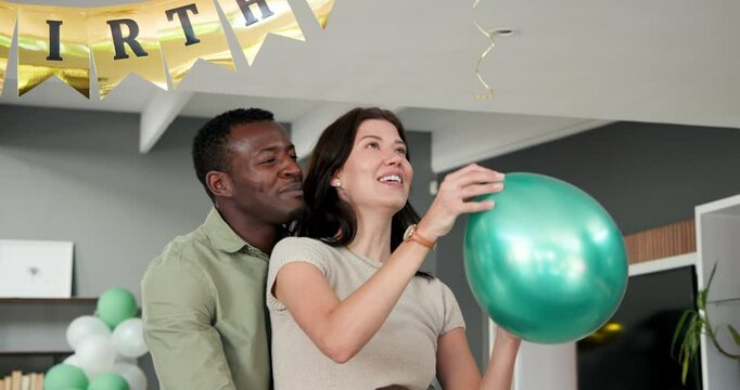 Happy multiracial and african american couple embracing and preparing decorations for a birthday par