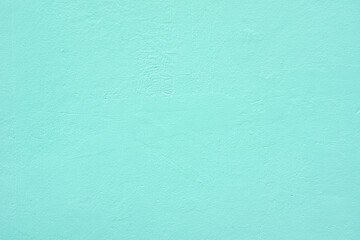 Obraz premium A smooth turquoise-colored concrete wall with a subtle textured surface. The plain background provides a minimalist aesthetic, suitable for design backdrops, mockups, or architectural concepts.