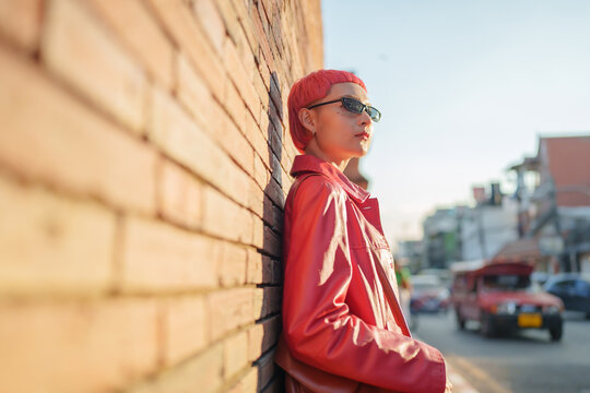 Gen z girl leather fashion with punk Asian woman tourist of local city Southeast Asia travel trendy pink hairstyle young female punk traveler walking around in town