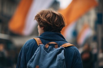 Person with backpack standing in city with out-of-focus flag and muted colors in background
