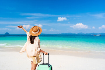 Young woman traveler with luggage relaxing and enjoying at beautiful tropical sand beach, Summer...