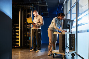 Team engaged in configuring servers in data center. Professionals collaborating on technical tasks...