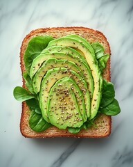 Sliced avocado on whole grain toast garnished with seeds and fresh spinach on marble background
