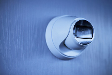 Close-up view of a modern surveillance camera affixed on a sleek wall suggesting security and...