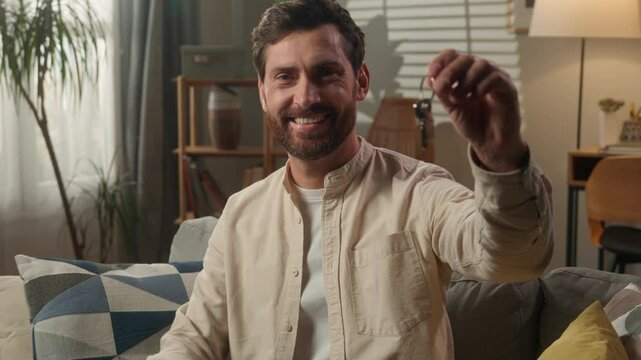Smiling adult man holding keys new home purchase happy male tenant guy businessman real estate buyer loan mortgage bank credit buying own apartment flat relocation moving day house insurance invest