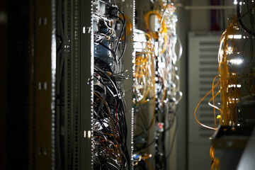 Complex network wiring and cables in data center with dim lighting illuminating the intricate...