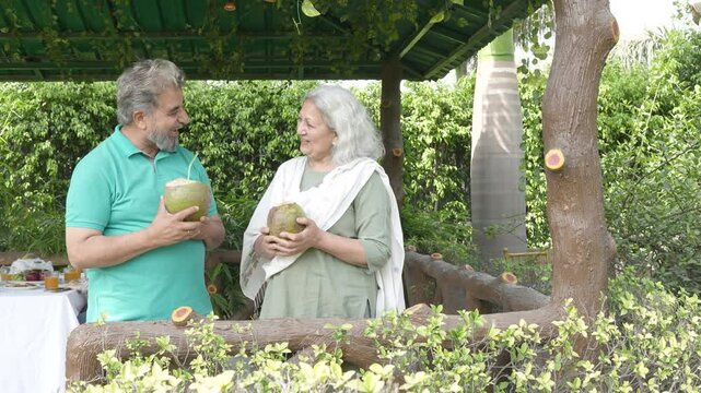 Retired senior indian couple enjoy coconut water in summer outdoor. Healthy drink. Retirement life. India