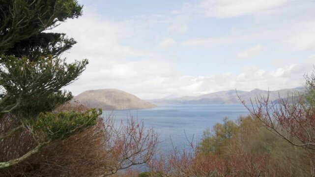 Scenic view of Lake Toya in Hokkaido, Japan, with snowy mountains in the background and a volcanic island in the center of the lake under a clear winter sky.