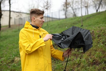 Man with broken umbrella under rain outdoors