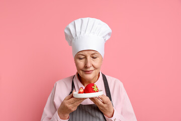 Professional confectioner with dessert on pink background