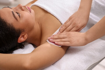 Woman undergoing wax epilation procedure in beauty salon