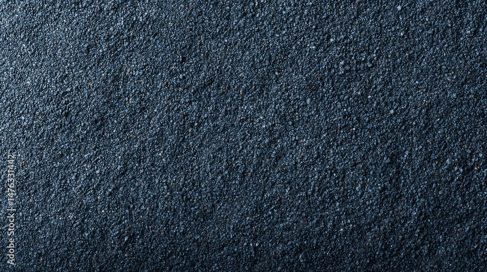 Poster Fine black sand grains are evenly spread across a surface, with subtle light highlighting their texture and depth, creating soft shadows for visual interest