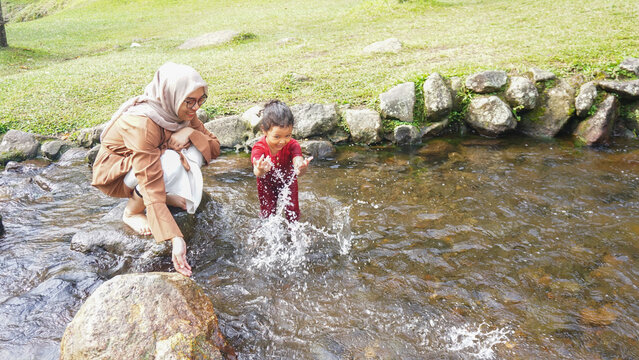 A daughter playing in a river with red clothes