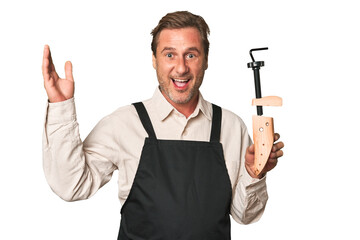 A middle-aged shoe maker receiving a pleasant surprise, excited and raising hands.