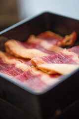 close-up image features several strips of raw beef neatly arranged in a black container at korean hotpot restaurant , showcasing the rich, marbled texture of the meat with its deep red and white hues.