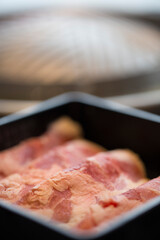 close-up image features several strips of raw beef neatly arranged in a black container at korean hotpot restaurant , showcasing the rich, marbled texture of the meat with its deep red and white hues.