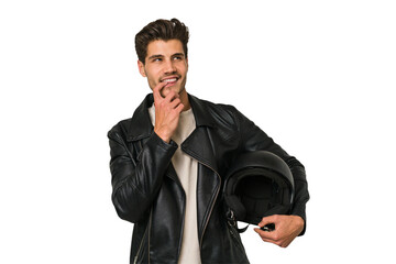 Young caucasian man holding a motrbike black helmet isolated relaxed thinking about something looking at a copy space.