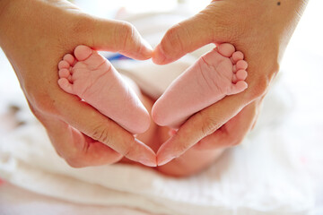 mother holding newborn baby feet of with heart shape