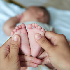 mother massaging newborn baby feet with care and love