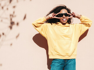 Beautiful woman with afro curls hairstyle.Smiling hipster model in yellow hoodie. Sexy carefree...