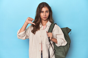 Young adventurer ready to explore with backpack showing a dislike gesture, thumbs down....