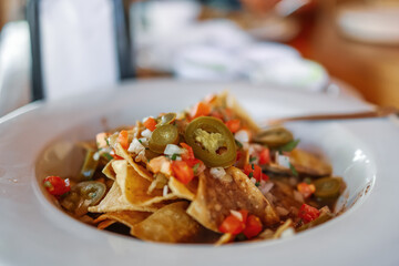 Plate of fresh Mexican style nachos with a spicy jalapenos and Jalapeno cheese sauce