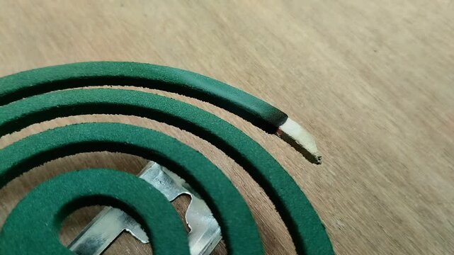 Mosquito coil in the shape of a circle that is burned with a wooden texture background