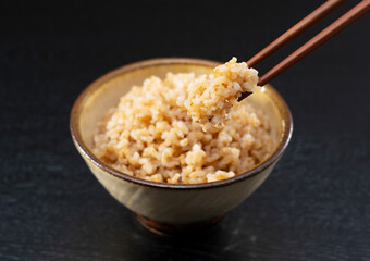 Freshly Cooked Brown Rice on a Black Background, Lifted with Chopsticks