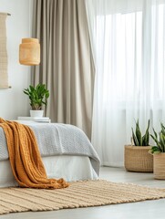 Bright bedroom interior detail showing bed with orange throw blanket and woven rug near plants and window