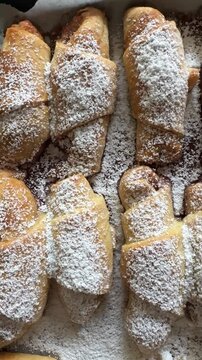 close up of fresh baked traditional Croation kiflice, jam-filled crescents dusted with icing sugar on baking tray