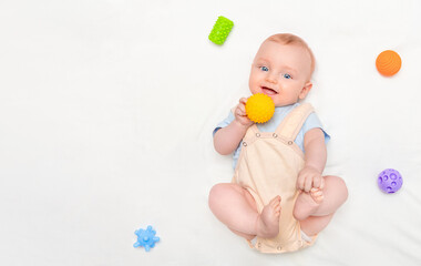 six month old baby playing with tactile colorful balls, top view