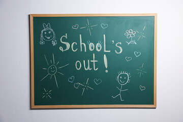 Fototapeta premium Phrase School's Out with exclamation mark and different drawings on blackboard