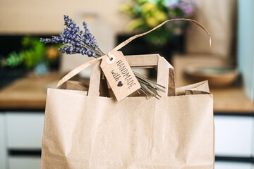 Close-up of a brown paper bag with a handwritten tag reading Handmade with love and a sprig of lavender. Handmade with love, emotional branding, artisan identity, heartfelt storytelling