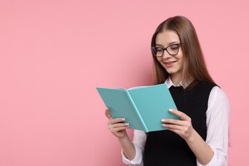 Fototapeta premium Teenage girl with book on light pink background. Space for text