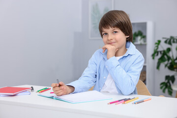 Cute little boy doing homework at table indoors