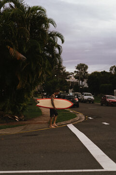 Man walks down the street with a surfboard