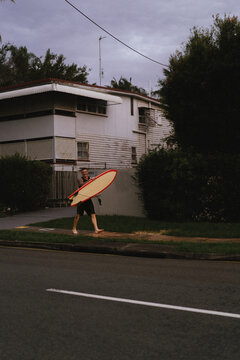 Man walks down the street with a surfboard