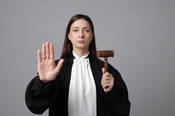 Judge with mallet showing stop gesture on gray background