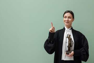 Judge with figure of Lady Justice on light green background, space for text