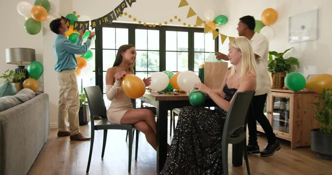 Group of happy multiracial, white and indian male and female friends preparing decorations for a bir