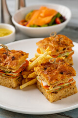 Square gourmet sandwiches with fries served on a white plate
