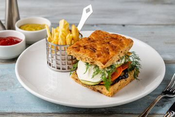 Gourmet vegetable sandwich with fresh herbs and fries on the side