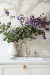 Interior Decor Still Life of Purple Flowers in White Pitcher Beside Brass Faucet on Marble Countertop in Kitchen Setting